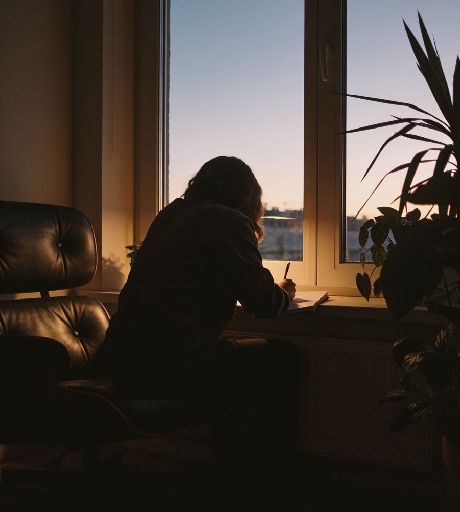 Someone writing at a window at dusk