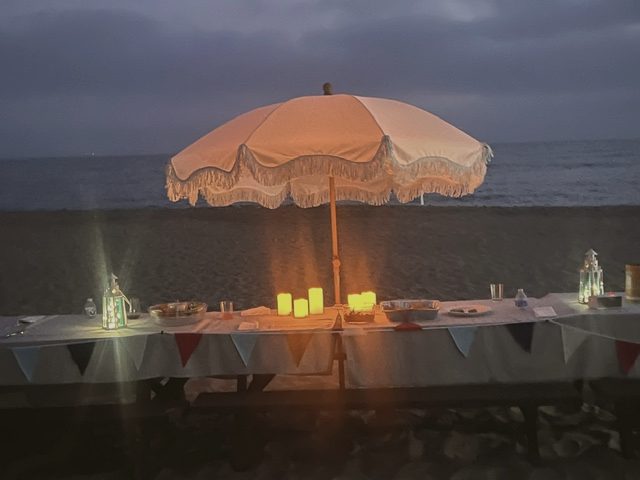 Candlelit table under a fringed umbrella at dusk